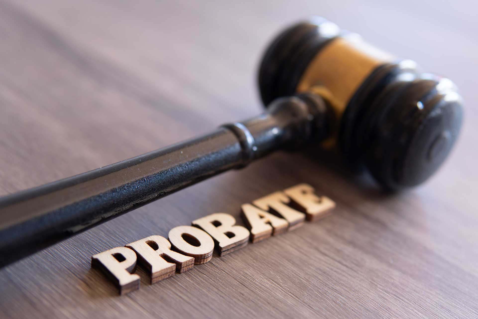 Gavel and wooden letters spelling "PROBATE" on a table, symbolizing the legal process of probate in estate management.